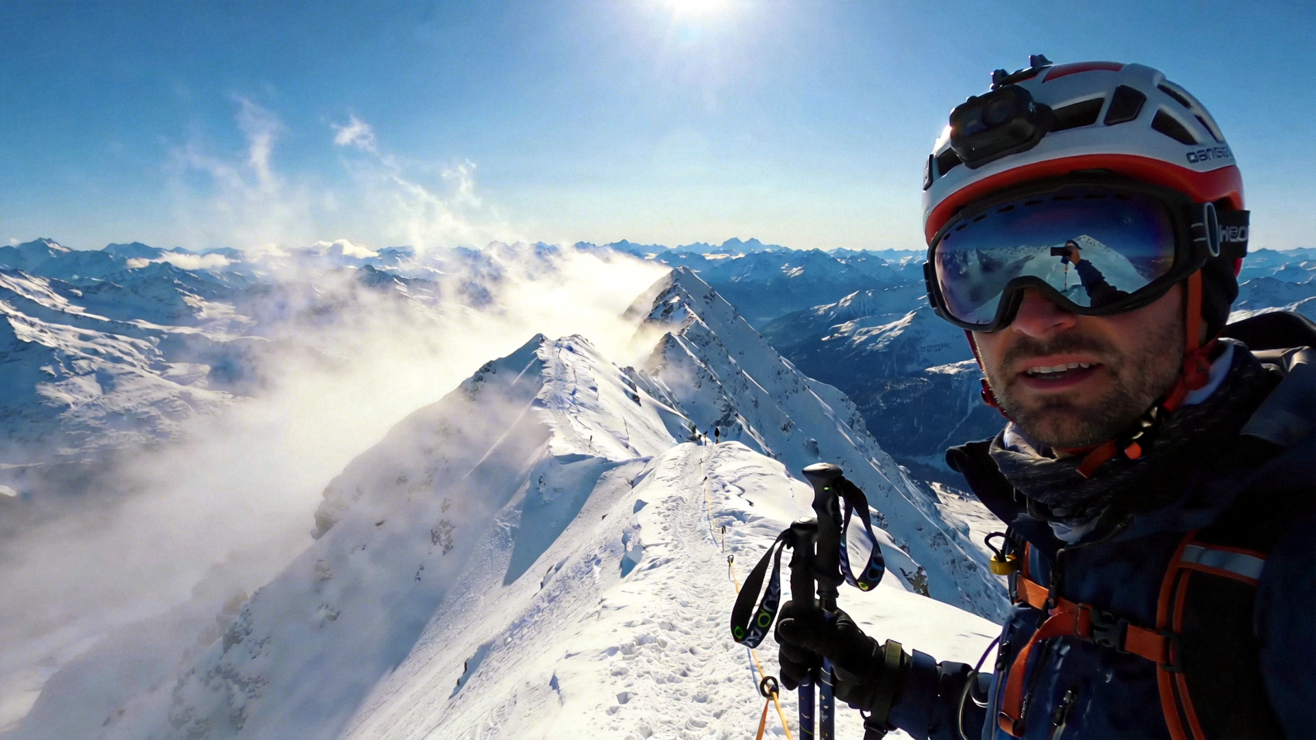 登山者在雪山之巅佩戴专业头盔手持登山杖的壮丽场景
